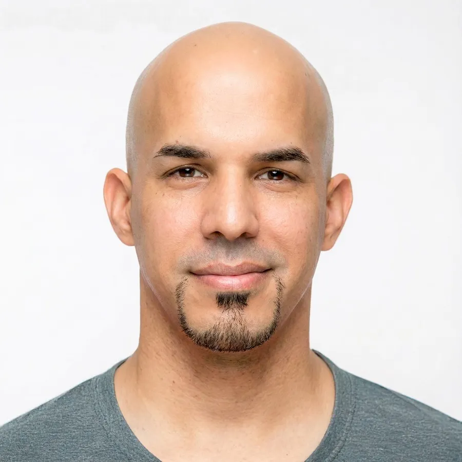 Headshot of Ben Oyola, smiling slightly, in a grey t-shirt against a white background.
