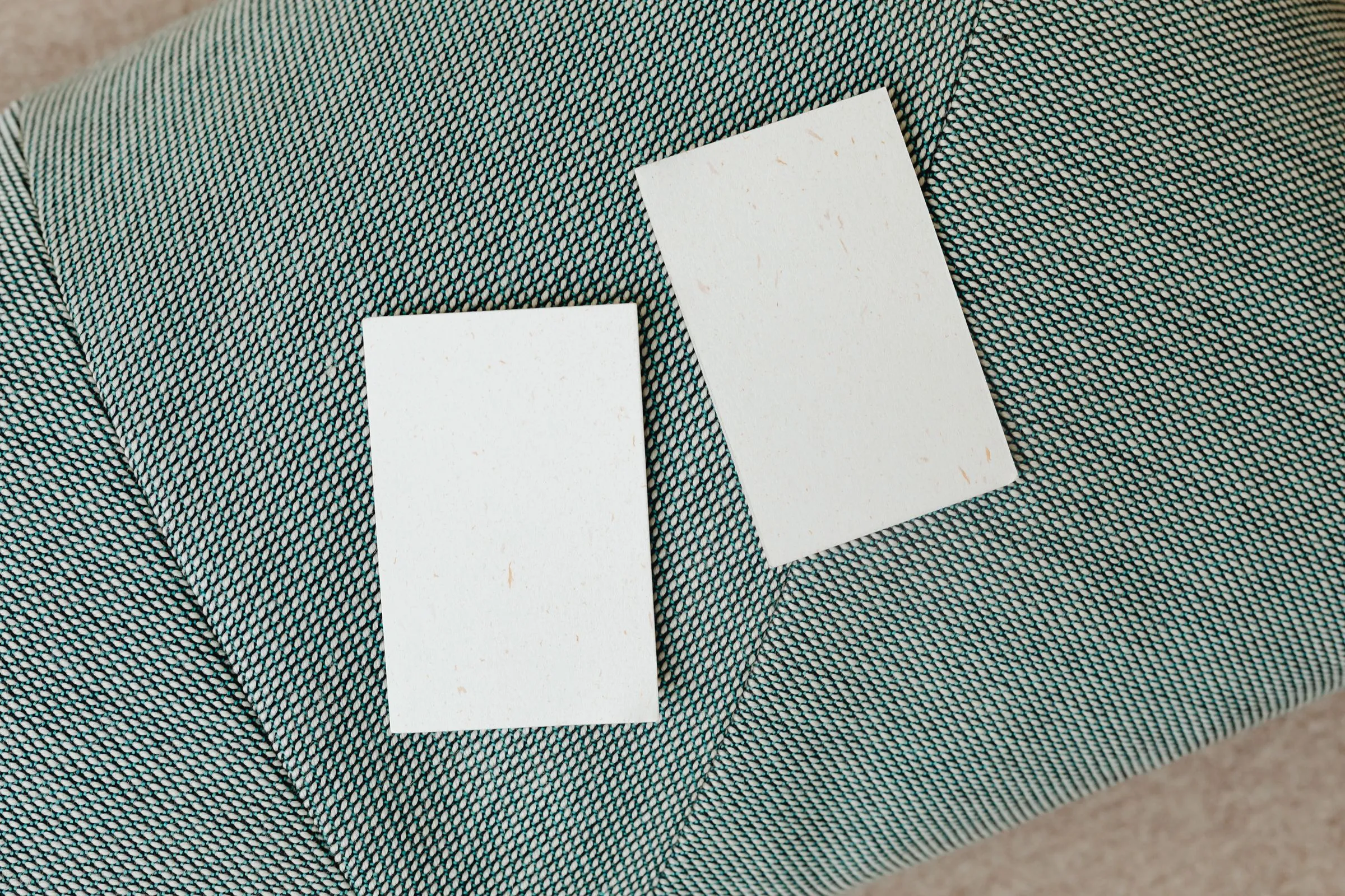 Two blank textured cards lying on sage green woven fabric.