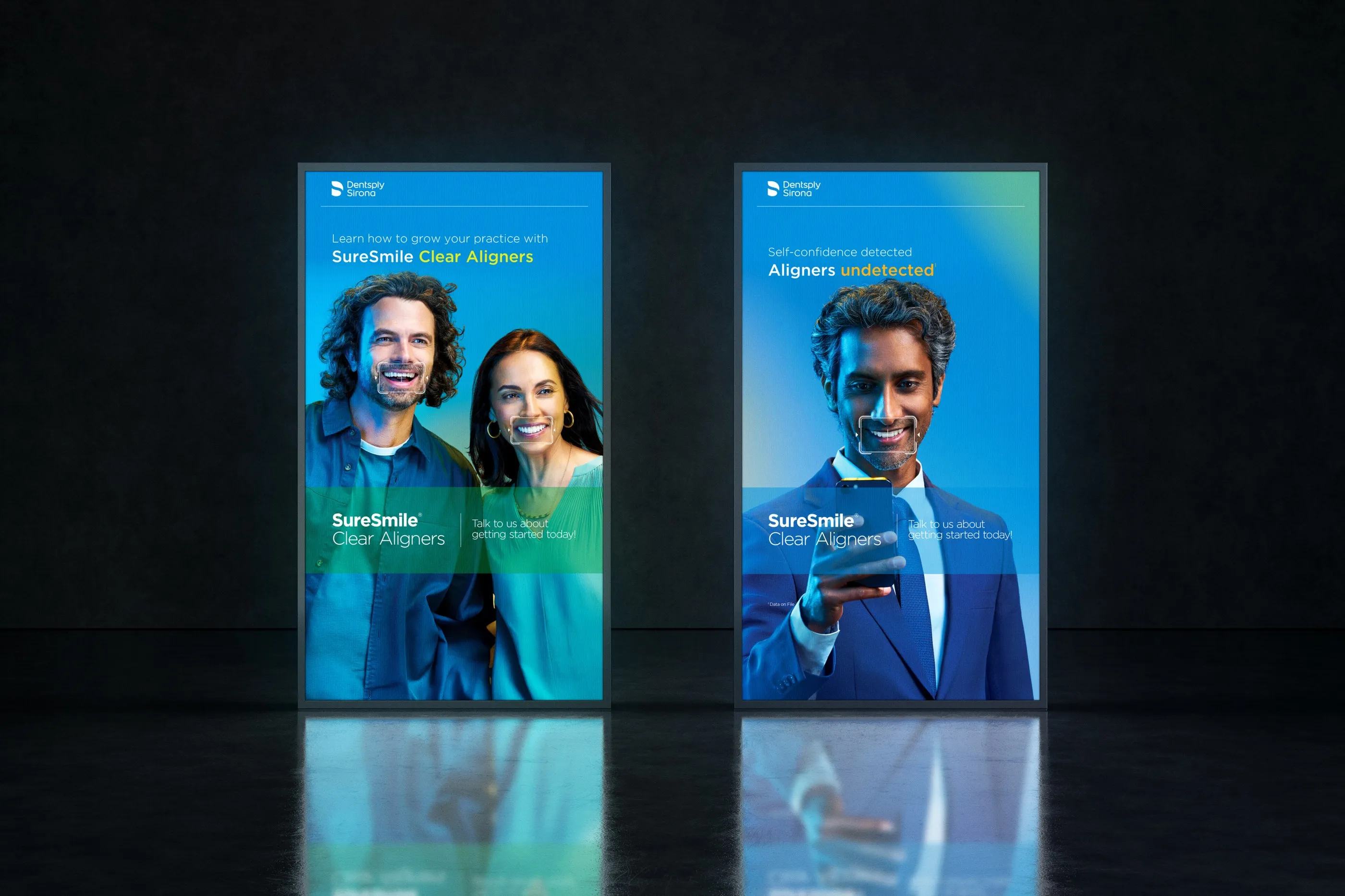 Two illuminated SureSmile Clear Aligners posters standing in a dark room.