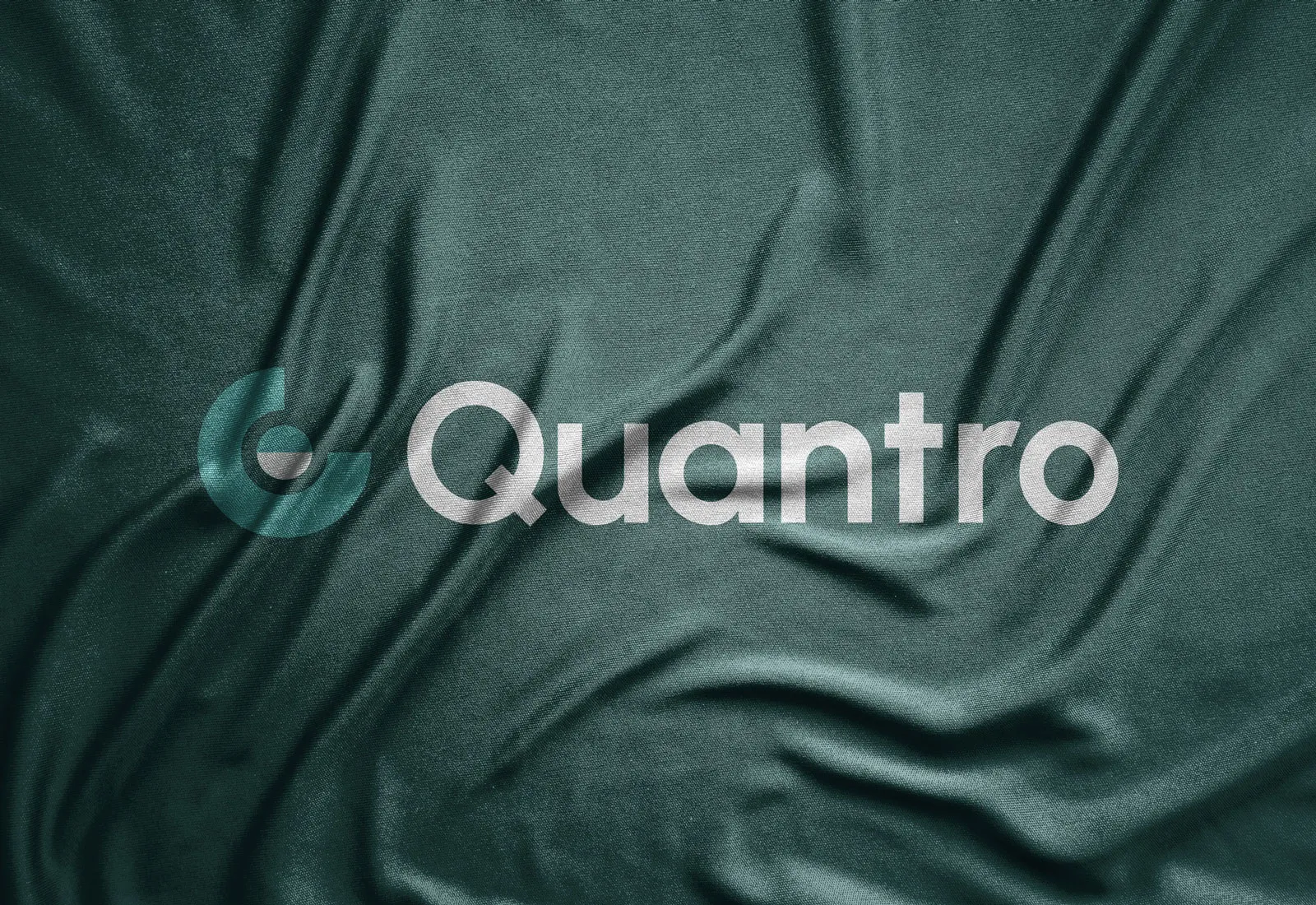 Quantro logo embossed on draped dark green fabric.