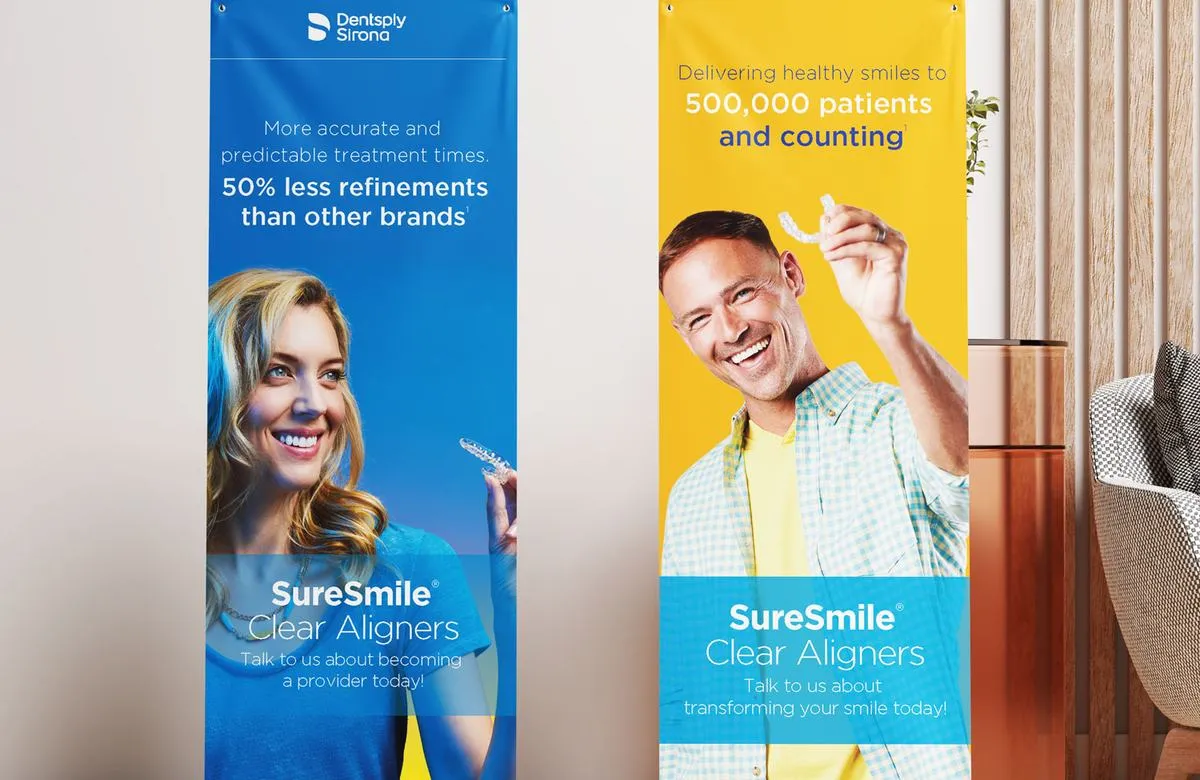 Two SureSmile Clear Aligners stand banners for Dentsply Sirona, one blue and one yellow, each with a smiling person holding an aligner.