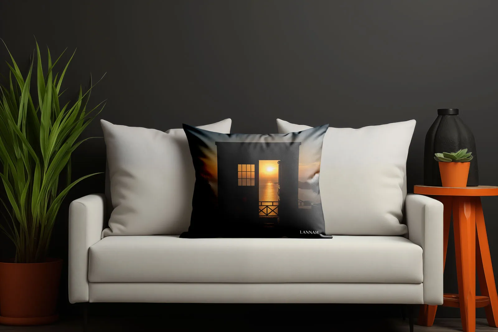 Black throw pillow printed with a sunset photo and the Lannah logo on a white sofa.