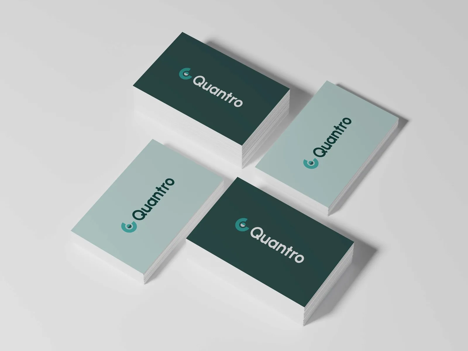 Stacks of Quantro business cards in dark green and pale sage.