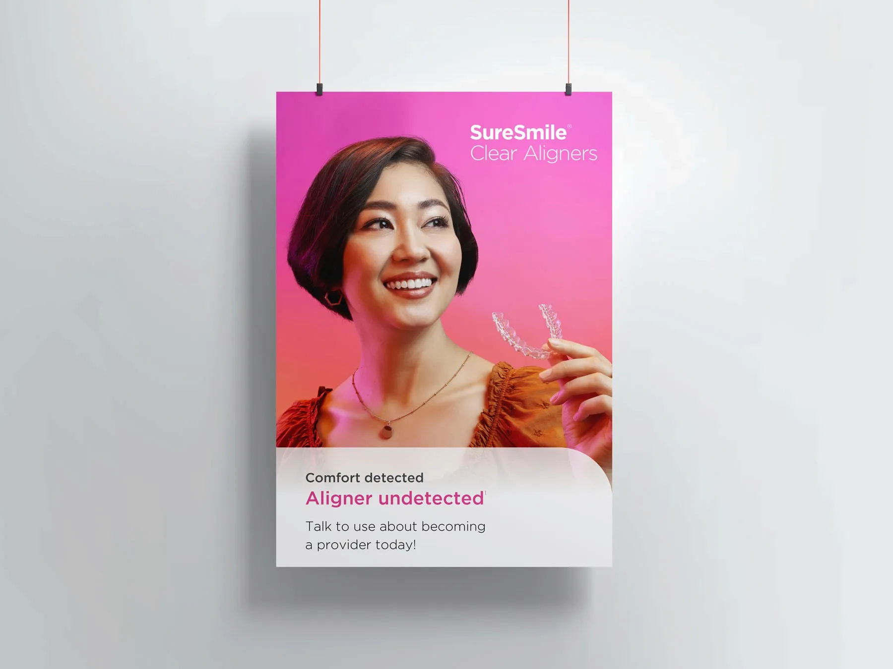 Hanging pink SureSmile Clear Aligners poster: "Comfort detected. Aligner undetected".