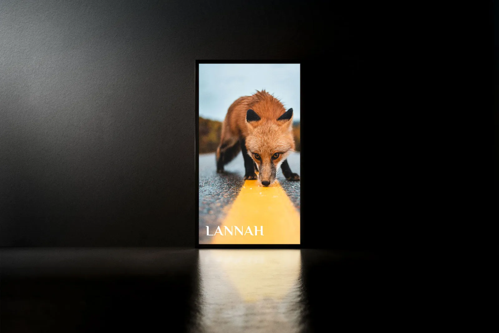 Tall glowing Lannah poster of a red fox in a dark room, reflected on the floor.