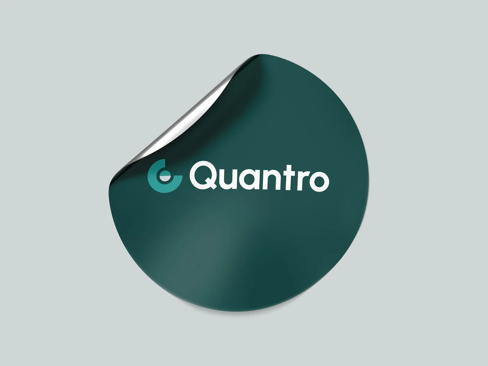 Round dark green Quantro sticker with a peeled edge.