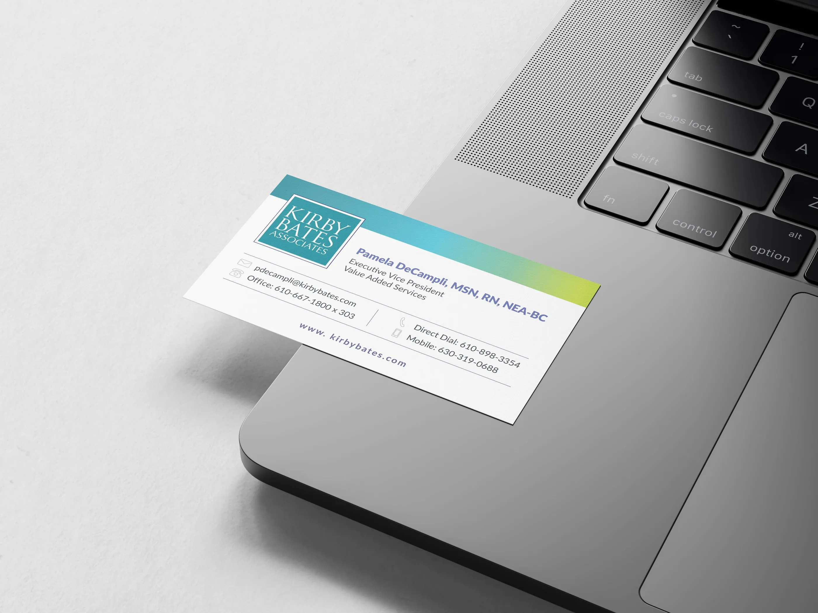 Kirby Bates Associates business card in teal and white resting on a laptop.
