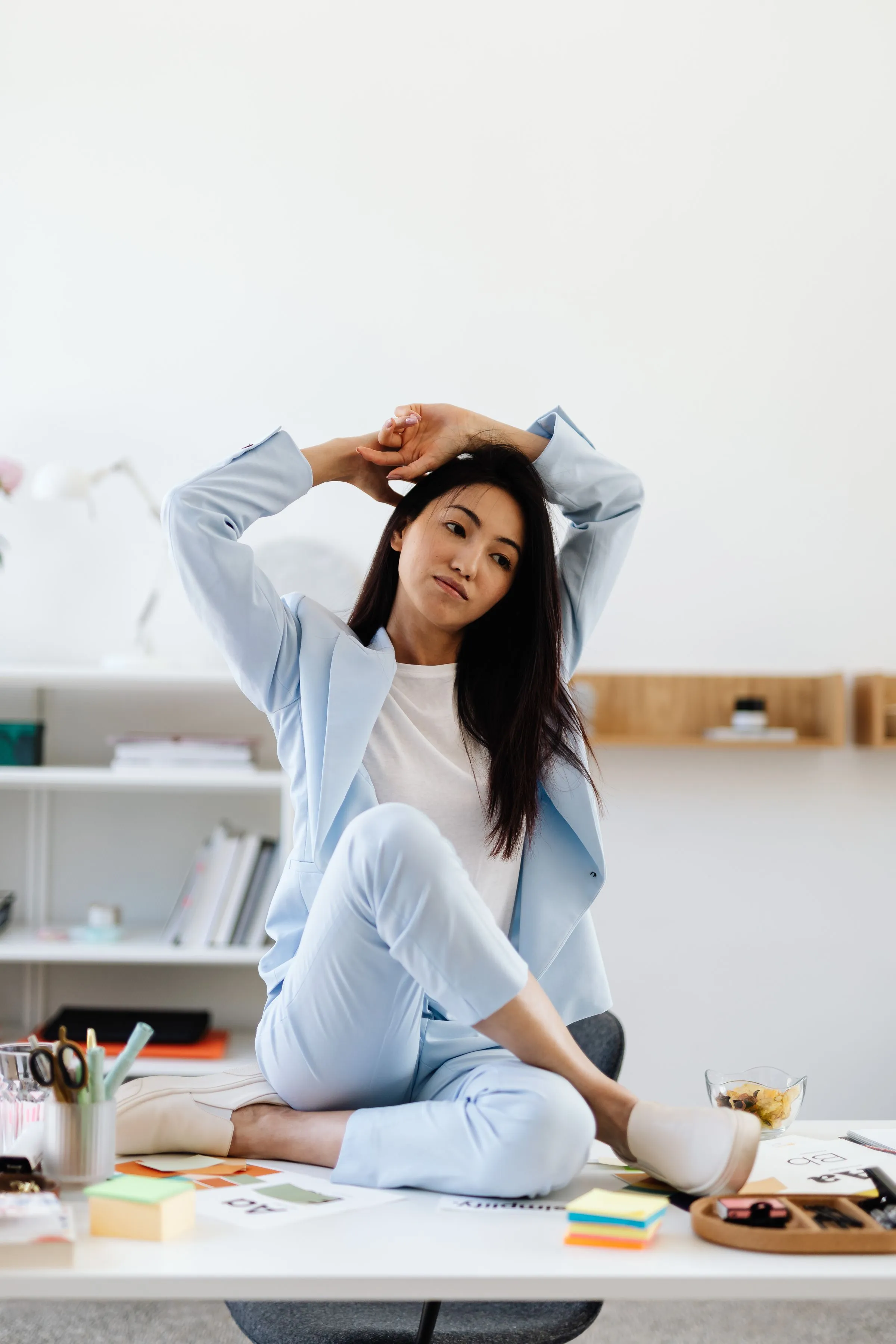 A woman stretching her arms over her head at her desk.