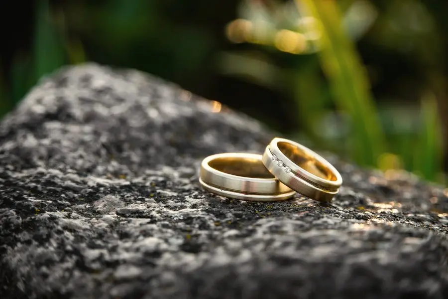 Two gold wedding bands resting on a dark speckled stone