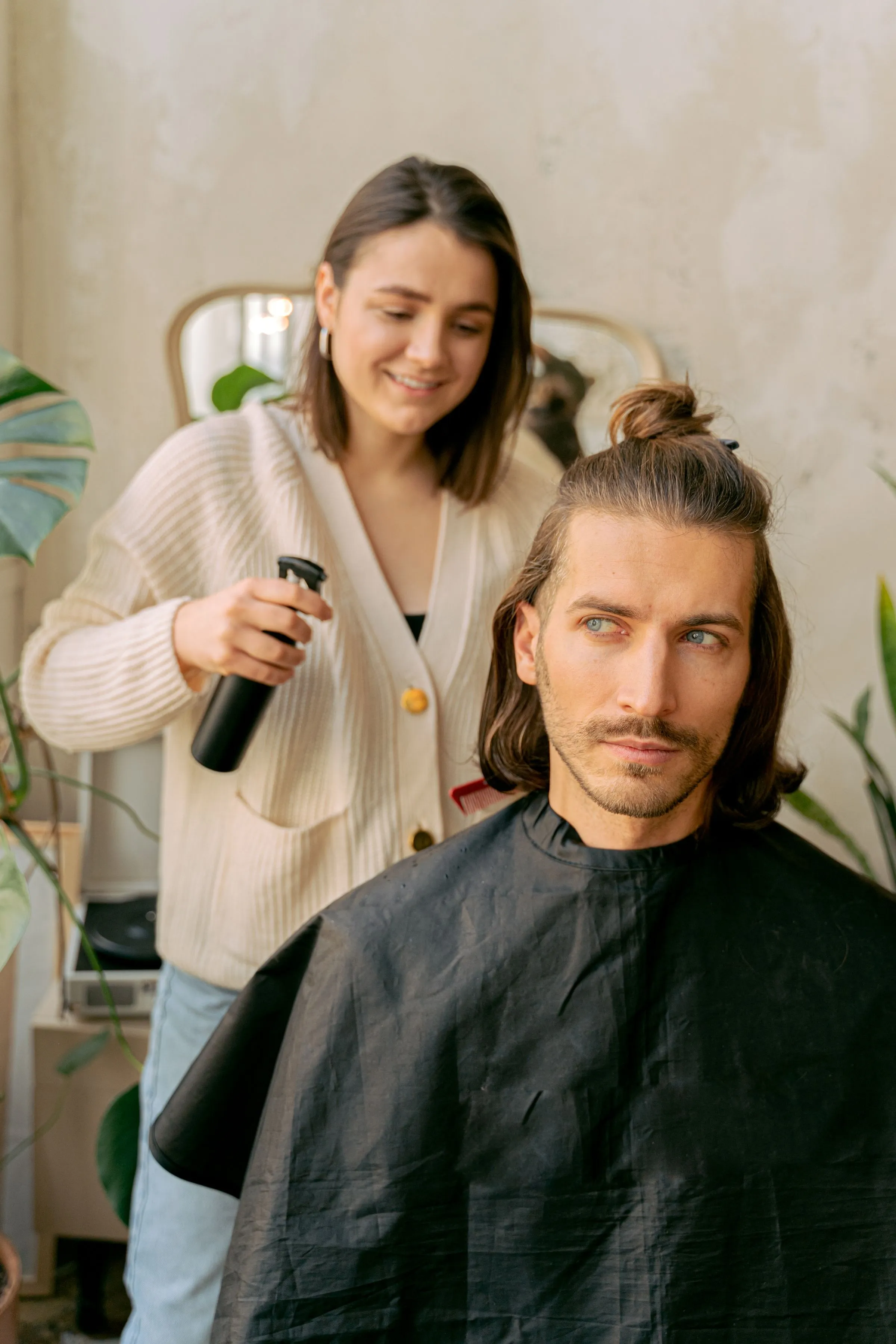 A stylist finishing a client’s hair with a spray of water in a bright studio.