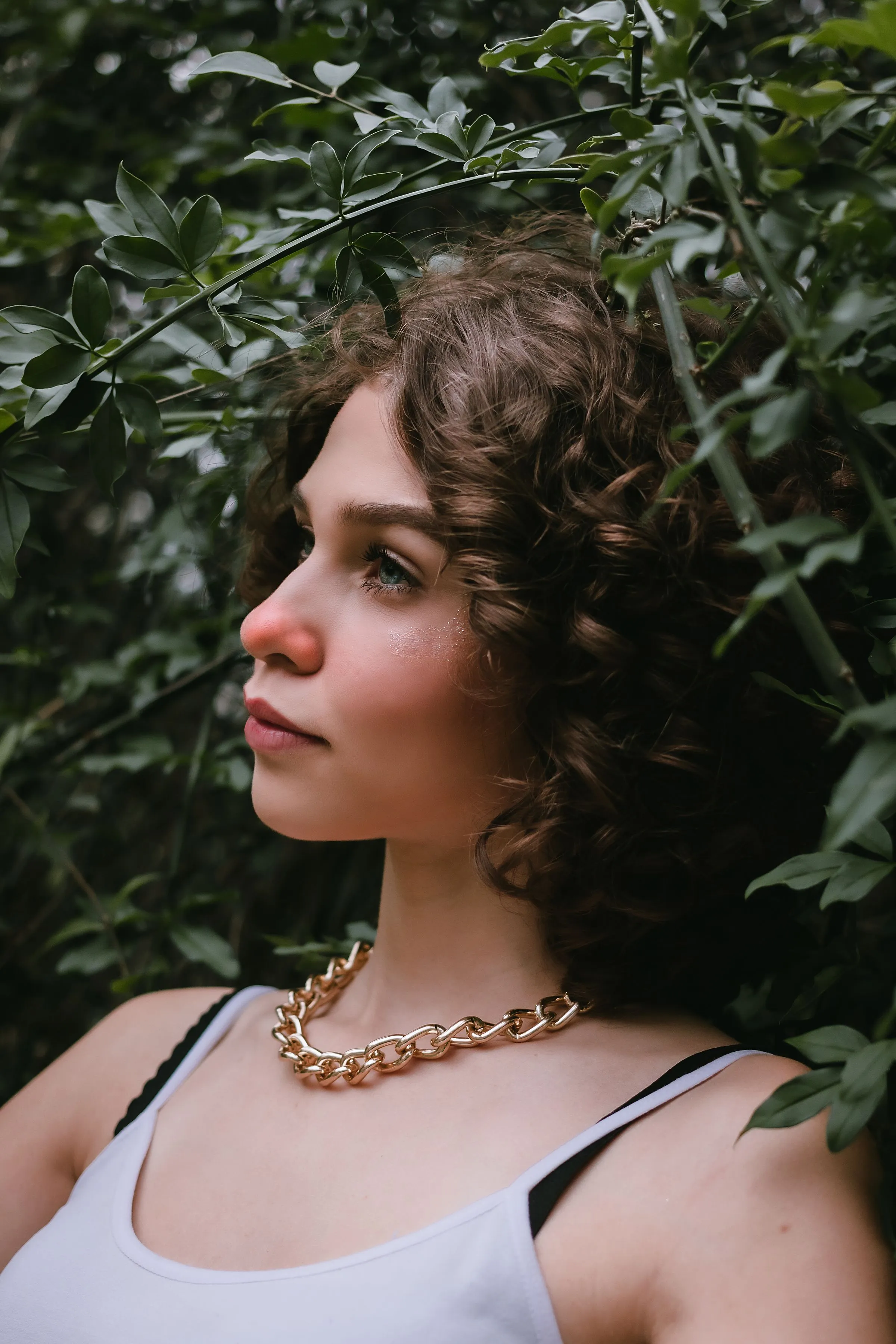 A woman with shaped brown curls in a garden.