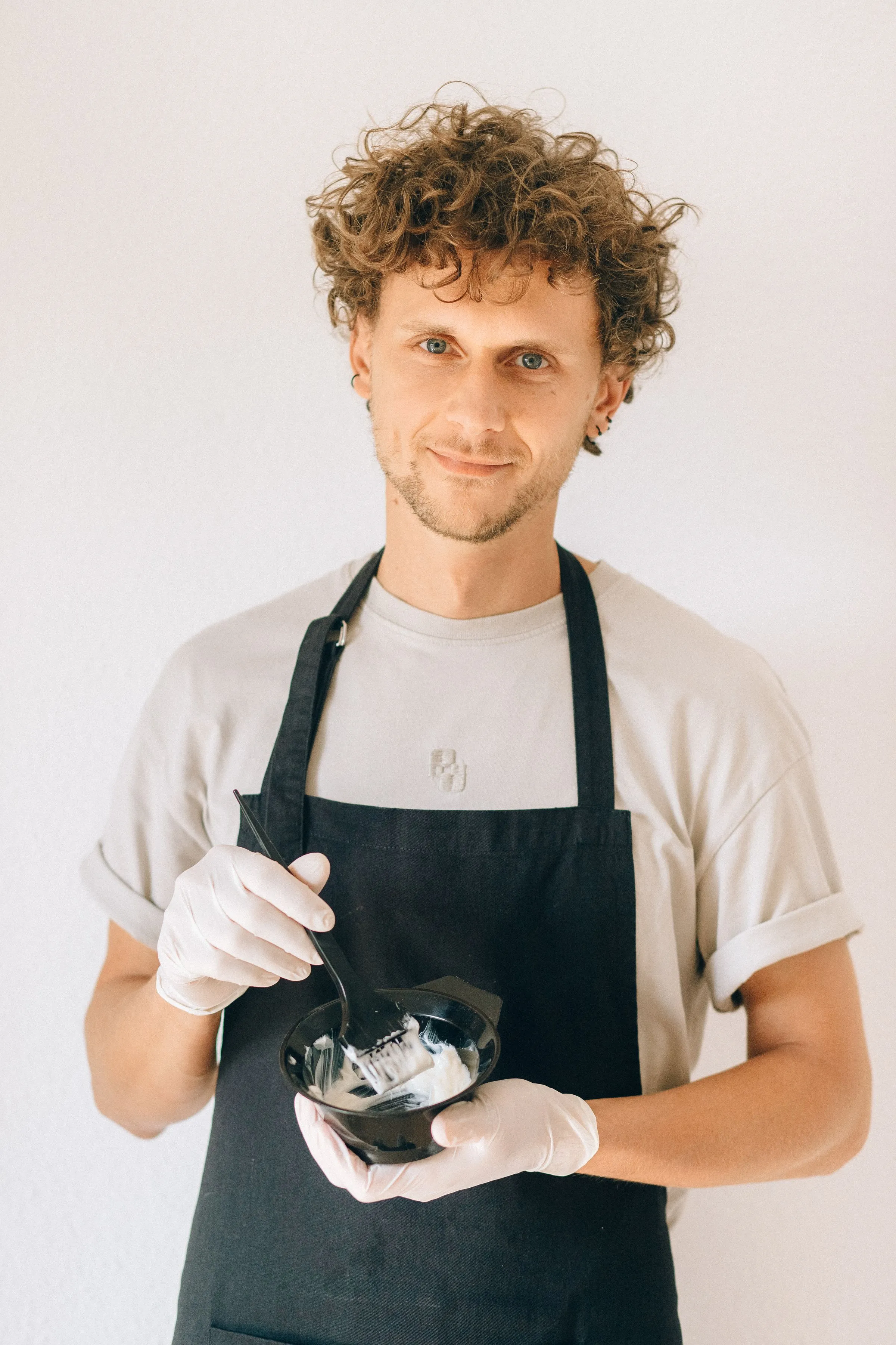 Theo in his apron, mixing color in a bowl.