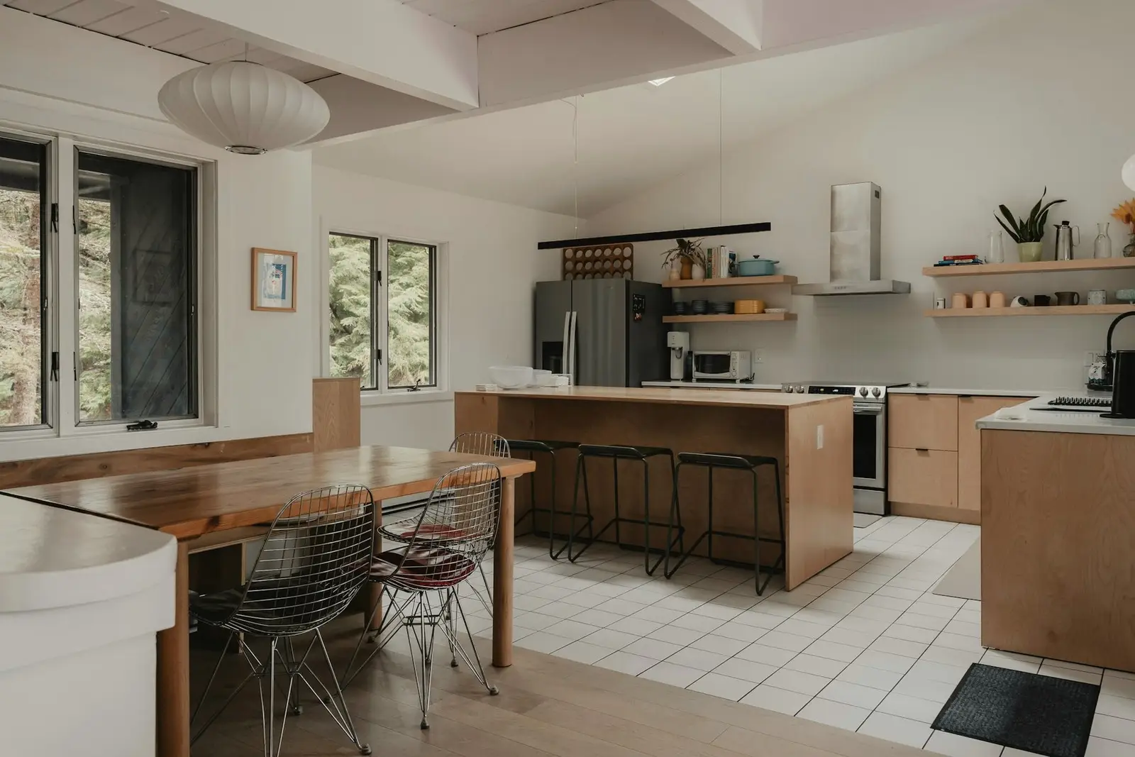 Kitchen and breakfast table with wire chairs, morning light from the side windows.
