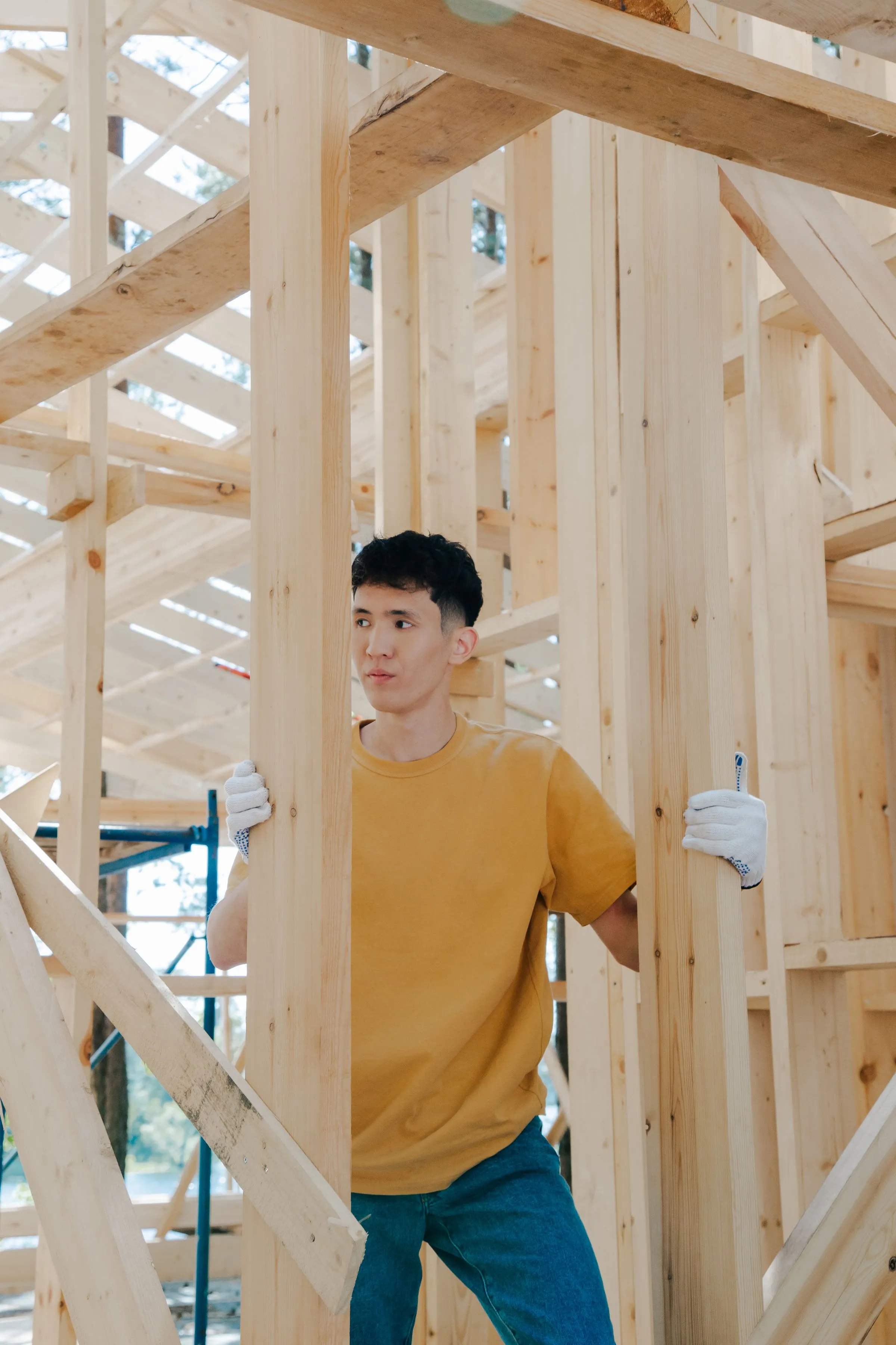 A crew member standing inside the wood framing of a new room.