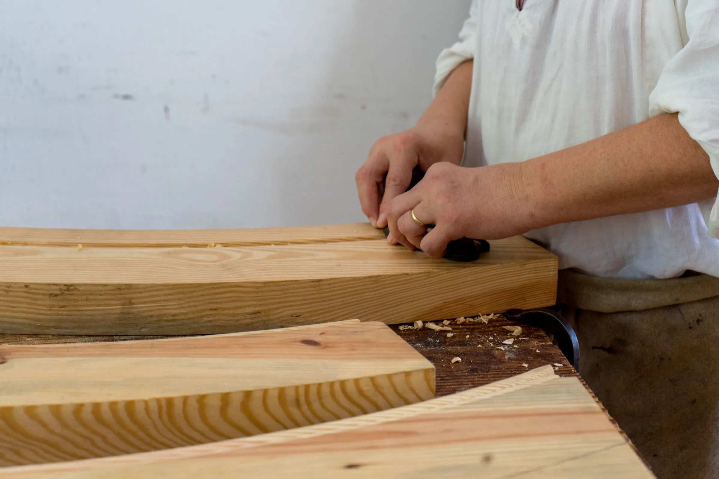 A carpenter’s hands checking a pine board on the workbench.