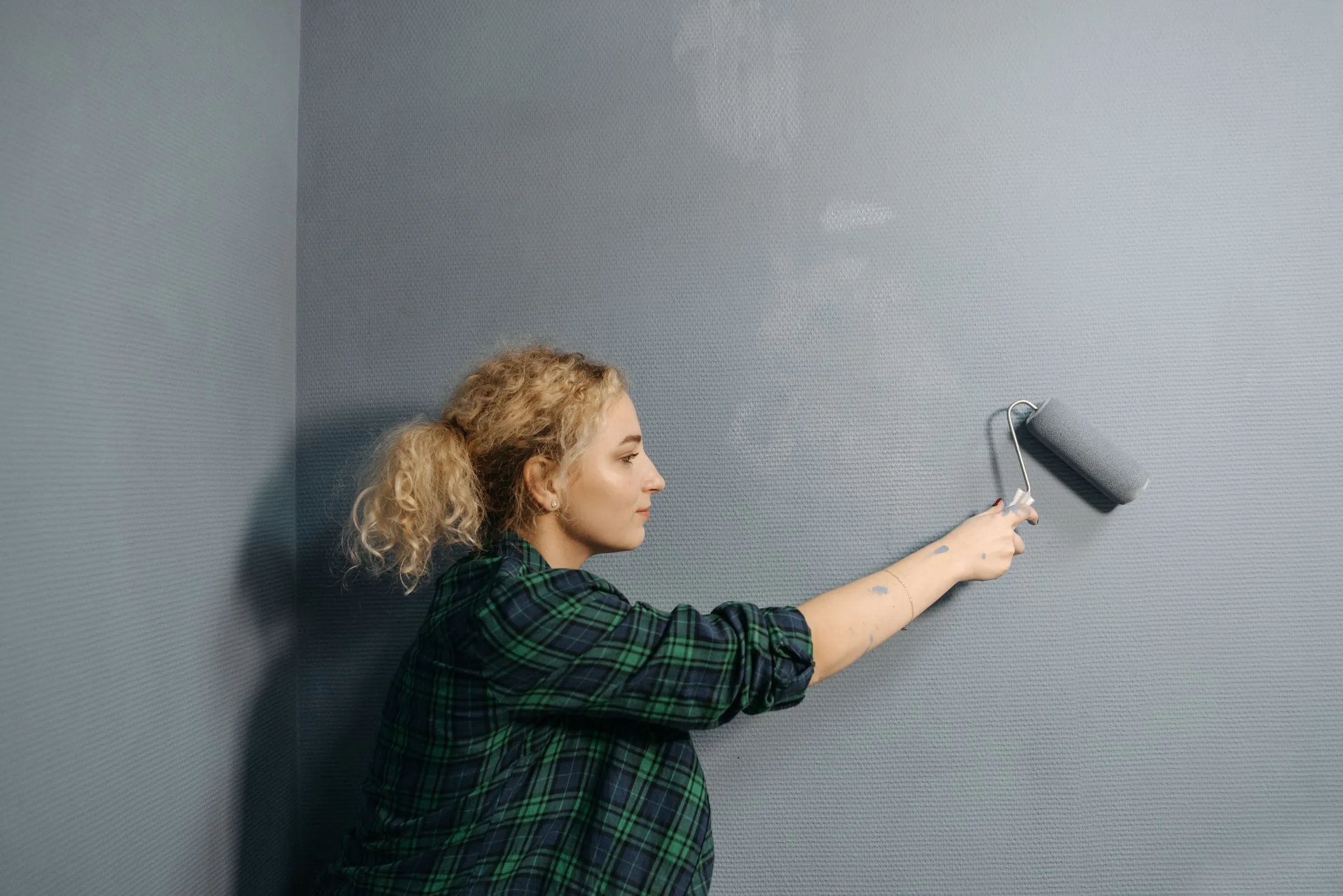 Painting a wall with a roller.