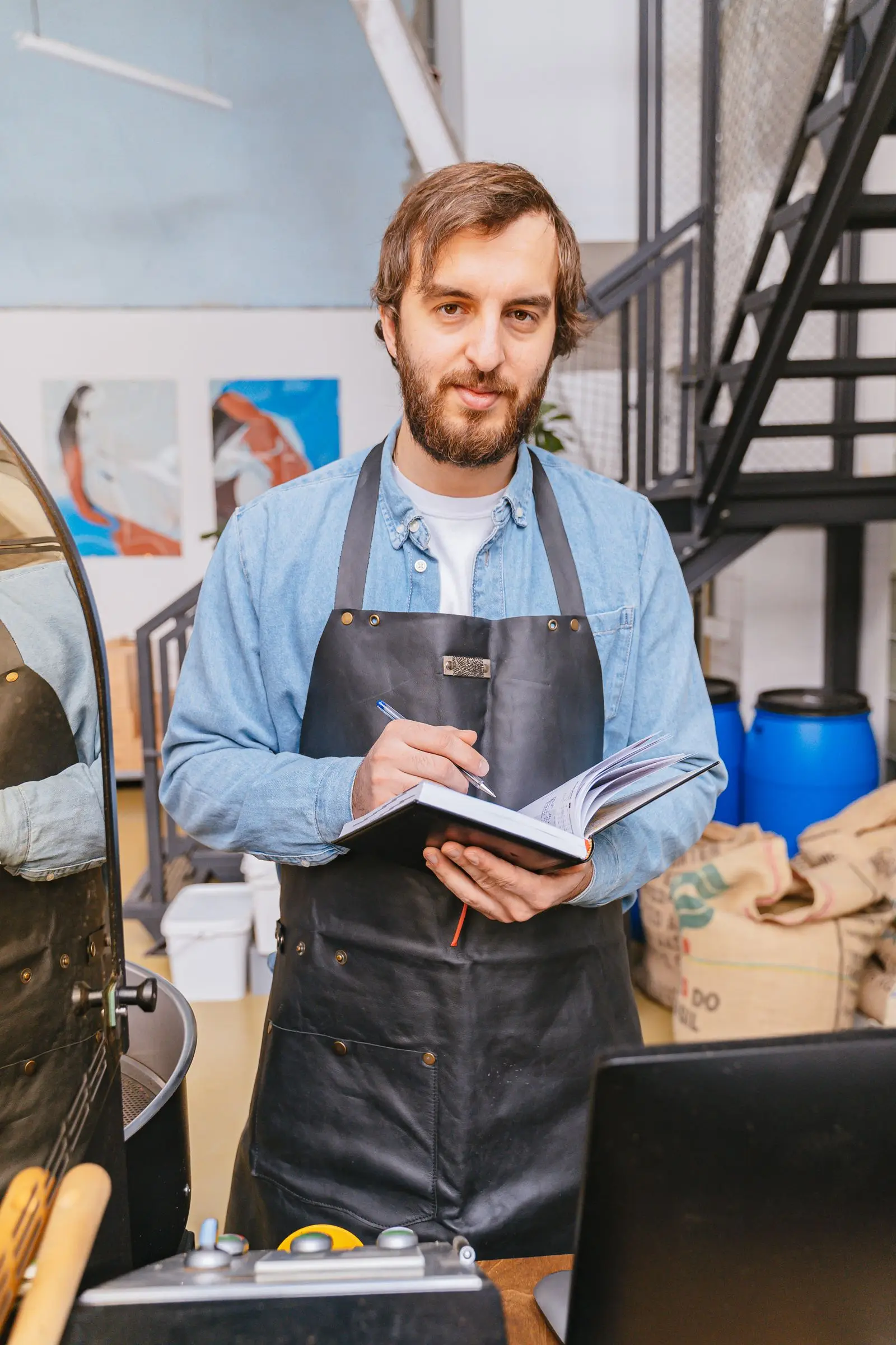 Chris Dalton, owner of Ember Coffee Roasters, holding a notebook in his roastery