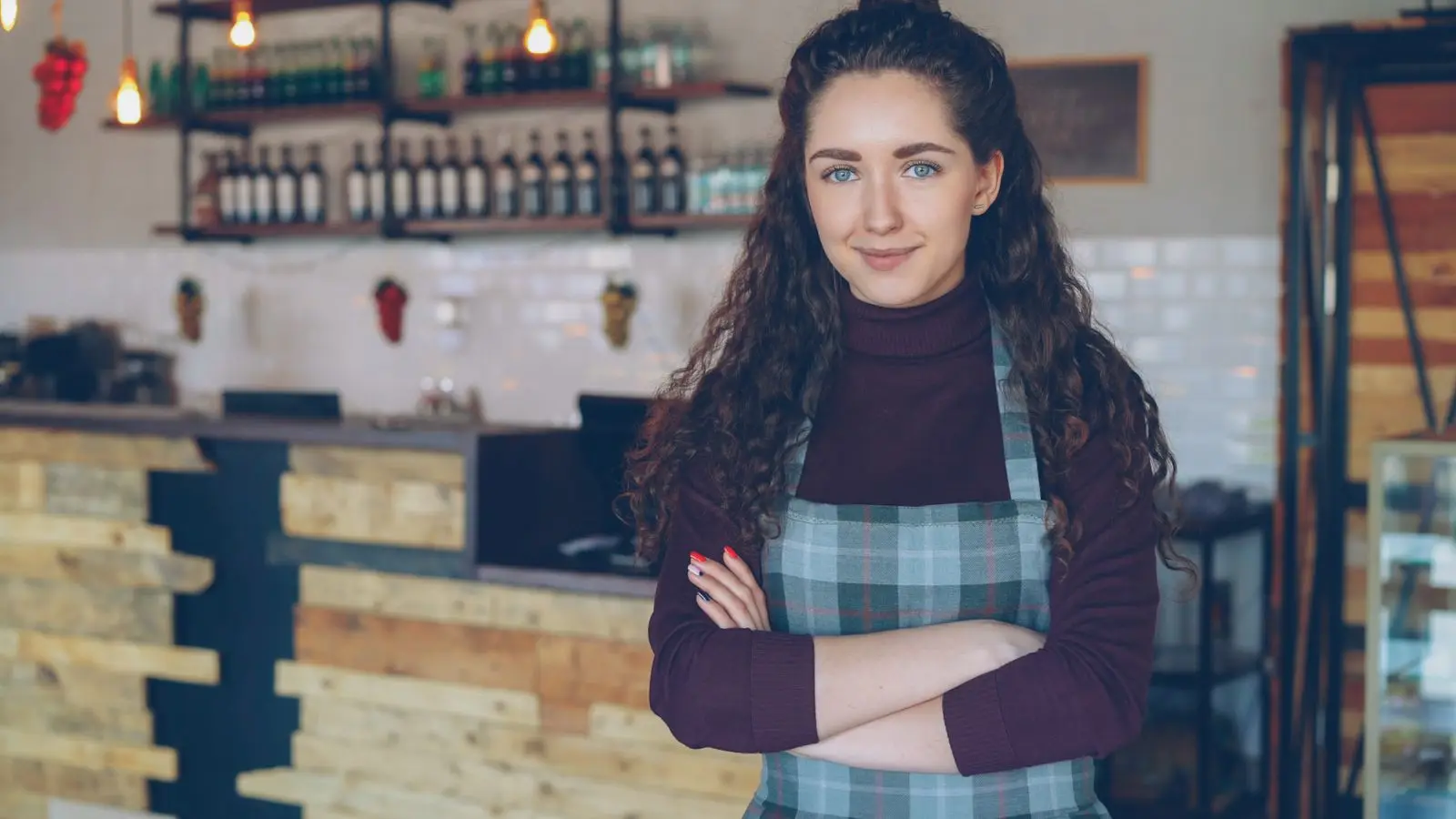Megan Hale, owner of Juniper Table, standing in her restaurant with arms crossed