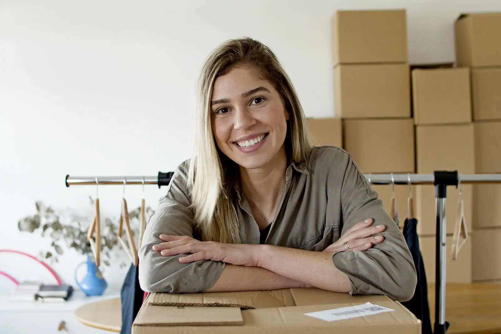Jessica Moore, founder of North & Pine Goods, smiling at her packing table with boxes behind her