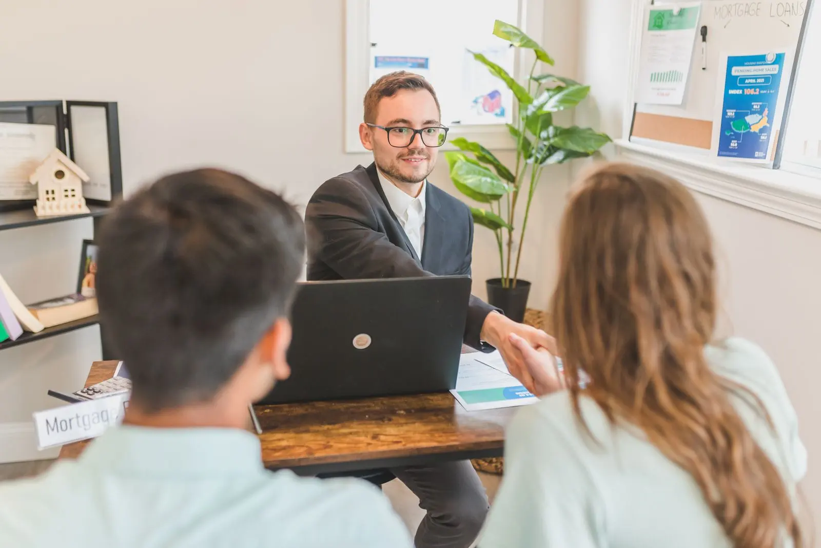 An advisor welcoming two new clients to a consultation in a bright office