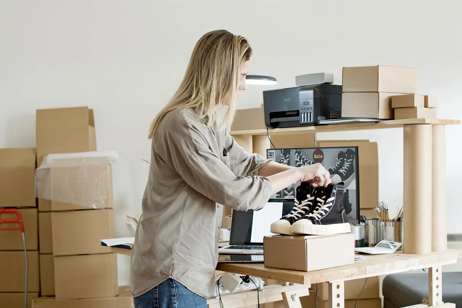 Jessica packing an order of shoes into a shipping box in her studio