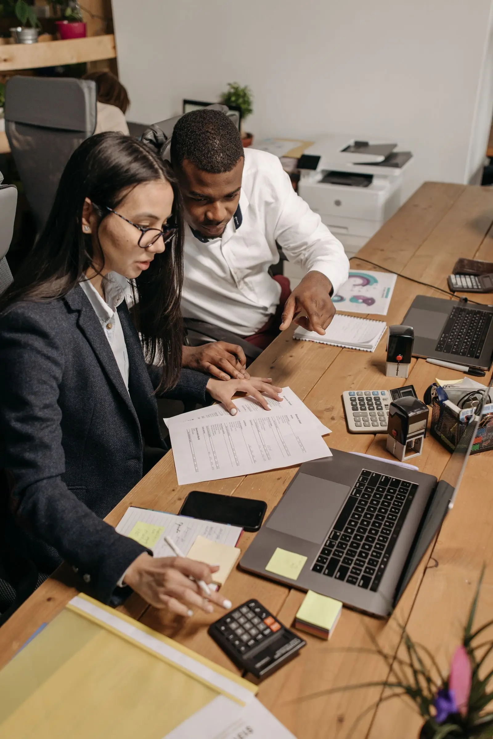 Two Quantro accountants reconciling a client’s ledgers with laptops and calculators