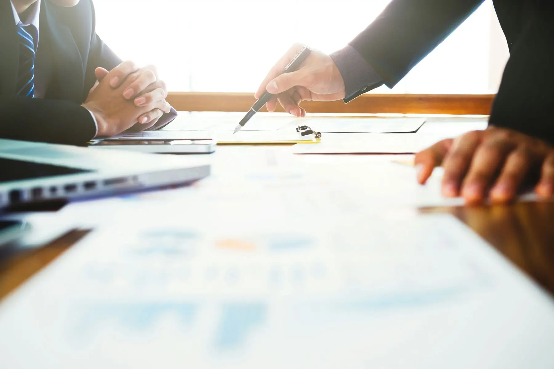 Business owner signing payroll documents across the desk from an accountant